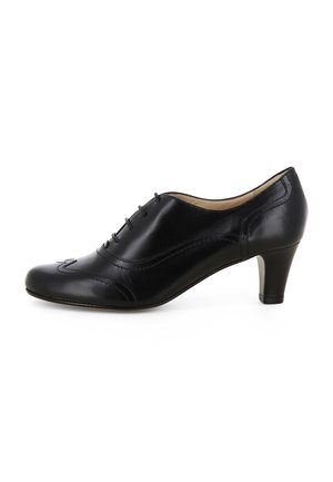 Scarpa Oxford da donna in pelle nera con tacco basso e cuciture decorative, vista laterale su sfondo bianco.