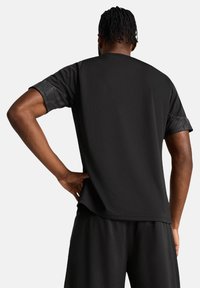 Zwart sport T-shirt met korte mouwen, voorzien van een textuurpatroon op de boorden. Heeft een relaxte pasvorm en een gladde stofstructuur.