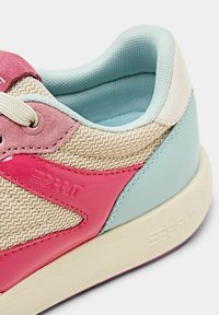 Baskets avec dessus en mesh beige, accents en cuir rose, détails bleu clair, semelle crème, avec logo visible sur le côté.