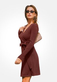 Burgundská proužkovaná zavinovací šaty s dlouhými rukávy a stahovacím pasem. Disponují hladkou texturou a délka sahá ke kolenům. Jsou doplněny slunečními brýlemi a taškou.