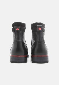 Botas de tobillo de cuero negro con un suave cuello de tela negra, costuras rojas detalladas y acentos de logotipo redondo en la parte trasera.