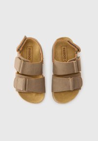 Καφέ σανδάλια με δύο ρυθμιζόμενους ιμάντες, επάνω μέρος από μαλακό δέρμα, εσωτερική σόλα φτιαγμένη από φελλό και εξωτερική σόλα από καουτσούκ. Το όνομα της μάρκας "FRIBOO" είναι ορατό στο εσωτερικό.