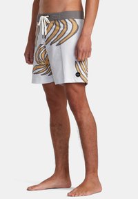 Herrbadshorts i vitt med abstrakta gyllene och grå ränder. Har en grå midjeband, snörning och ett svart logopatch.