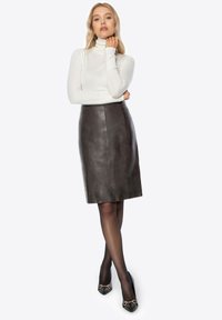 Biały top z długim rękawem i golfem, zestawiony z szarą spódnicą ze skóry o długości do kolan. Czarnie buty na obcasie ze złotymi akcentami. Gładka faktura całości.