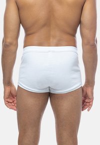 Costume da bagno bianco a coste con una morbida vita elasticizzata, visto da dietro, che evidenzia la vestibilità aderente e la superficie liscia.