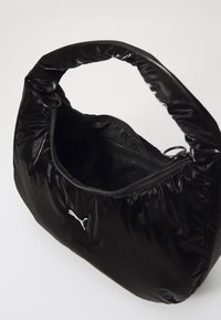 Sac à main synthétique noir au design arrondi et gonflé. Possède une fermeture éclair et un logo blanc à l'avant. Texture lisse, finition brillante.