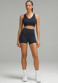 Zwarte sportbeha en hoog aangesloten shorts, gemaakt van rekbare stof. De top heeft een V-hals ontwerp en de shorts zijn snug aanzettend.