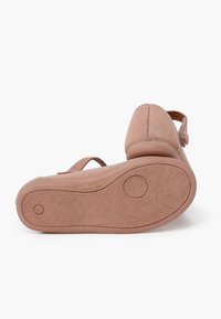 Zapato de ante rosa con una suela texturizada, correa ajustable y un detalle de costura minimalista. El tacón es bajo y tiene una forma redondeada.