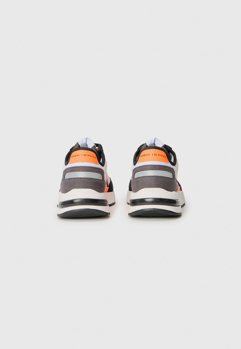 Zapatillas deportivas con una parte superior de malla gris, acentos naranjas, detalles en negro y un cuello acolchado; una mediasuela blanca con una suela exterior negra texturizada.