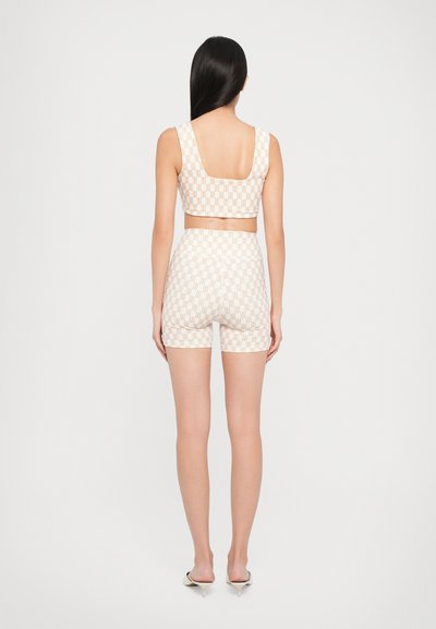 Tvådelad outfit bestående av en mönstrad crop top och högmidjade shorts i en ljus färg med ett rutmönster, som visar på ett mjukt tyg och en figurnära passform.