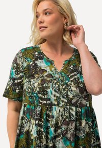 Blumenkleid in Grün-, Blau- und Brauntönen, mit V-Ausschnitt, kurzen Ärmeln und gerafftem Taillenbund. Das Material wirkt leicht und strukturiert.