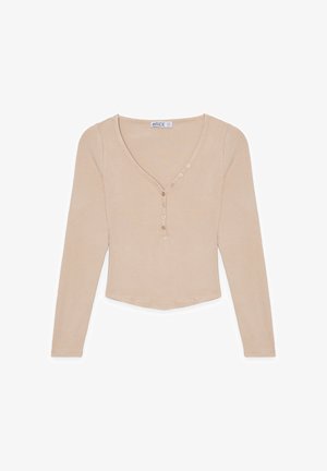 Top de manga larga de color beige con relieve, escote en V y cinco botones a lo largo de la tapeta. Textura suave y dobladillo cortado con bordes redondeados.