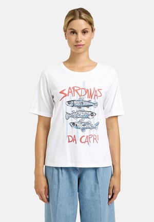Woman wearing white short-sleeve T-shirt with three illustrated sardines and red text "SARDINAS DA CAPRI" on front, paired with light blue pants.