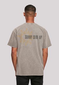 Gray graphic t-shirt featuring a sun design with "SUNNY SIDE UP" text in black and yellow on the back. Short sleeves and relaxed fit.