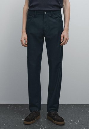 Chino verde scuro realizzati in cotone, con vestibilità classica, gambe dritte, tasche frontali e chiusura con bottone singolo. Superficie testurizzata.
