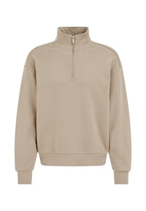Pull-over beige à manches longues avec fermeture éclair quart, col montant, poignets et ourlet côtelés, et texte brodé subtil sur le côté gauche de la poitrine.