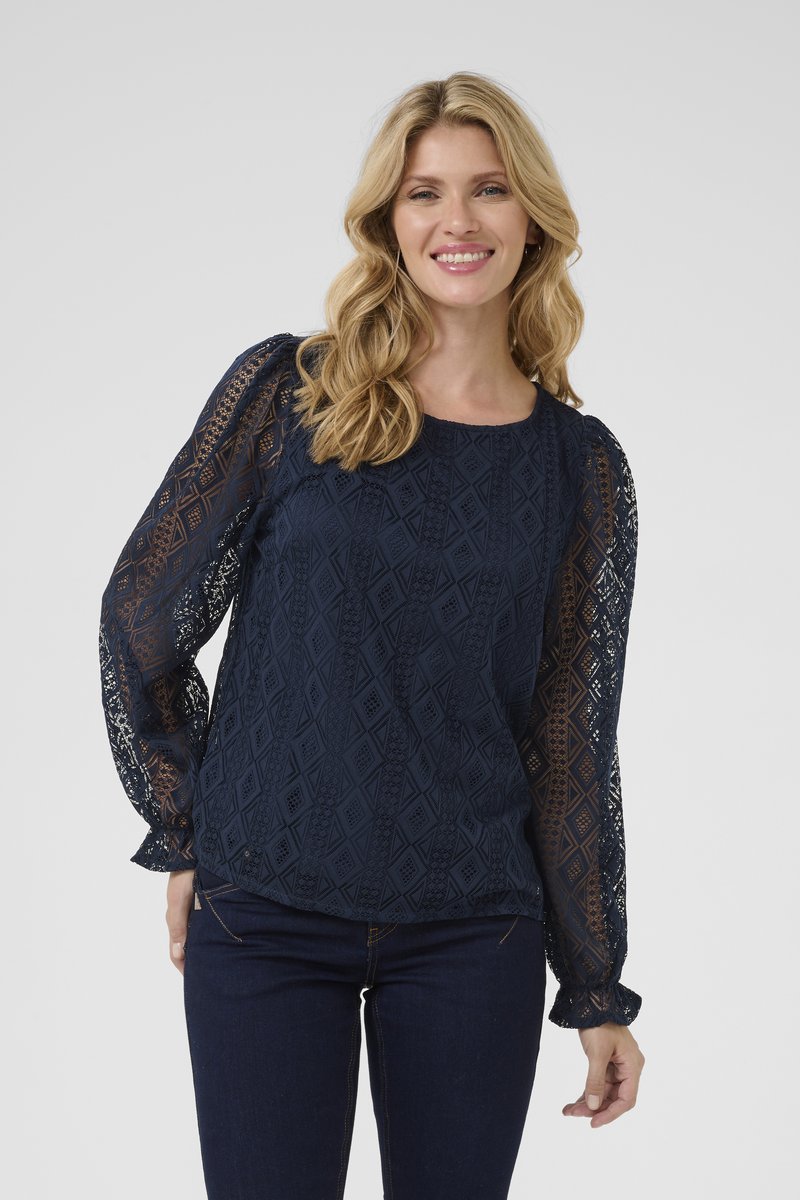 Marineblaues Langarmshirt aus strukturiertem Spitze mit Diamantmustern und gerafften Manschetten. Kombiniert mit dunklen Jeans.