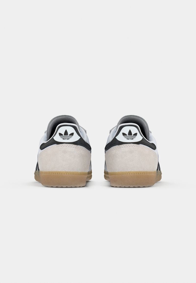 Ein Paar weiße und schwarze Adidas-Sneaker mit Gummisohlen, von hinten gezeigt, mit dem Adidas-Trefoil-Logo auf der Ferse.