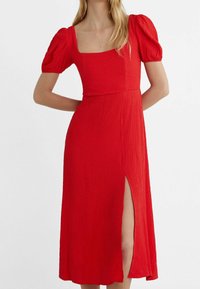 Punainen mekko neliömäisellä pääntiellä, puffihihat, teksturoitu kangas ja sivuaukko. Keskipitkä malli, jossa on sovitettu vartalo ja valuva hame.