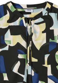 Haut avec imprimé géométrique abstrait en noir, bleu, vert, jaune et crème, doté d'un col rond et d'une ouverture keyhole à l'avant avec liens.