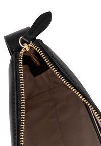 Interno di borsa in pelle nera con chiusura a cerniera dorata. Tessuto liscio e fodera beige visibile all'interno. Tiretto della cerniera attaccato.