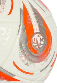 Hvid fodbold med orange og sølv detaljer, geometriske mønstre og en struktureret overflade med et trykt logo i centrum.