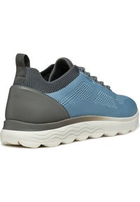Scarpa atletica blu e grigia con tomaia in rete testurizzata, collo imbottito e suola bianca ondulata. Caratterizzata da un design leggero e materiali resistenti.
