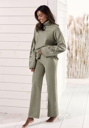 Olive green knit sweater with a high collar and oversized sleeves. Coordinating wide-leg pants with brand logo printed vertically.