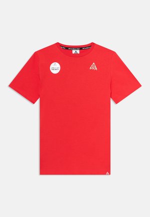 Rood T-shirt met korte mouwen en ronde hals met kleine Nike ACG-logo's op de voorkant en een wit rond label met de tekst "Check out the back!"