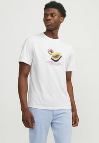 Witte katoenen T-shirt met een graphic van een doorgeknipt fruit met paarse en gele details. Hieronder staat de tekst "Originals © 1990 Ontworpen in CPH."