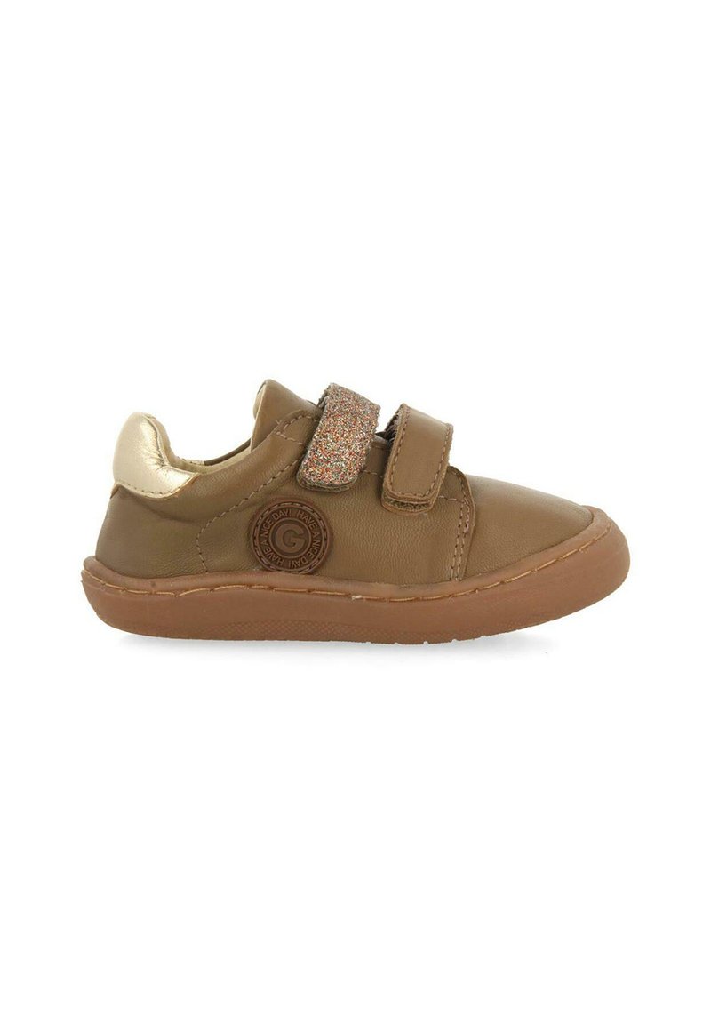 Zapato de cuero marrón con punta redondeada, adornos dorados en el tacón y una correa brillante. Suela de goma y detalle de costura a lo largo de los bordes.