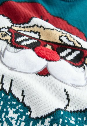 Sweter robiony na szydełku z motywem Świętego Mikołaja, prezentujący czerwoną czapkę, białą brodę oraz teksturowany czerwony nos na tle w kolorze teal.
