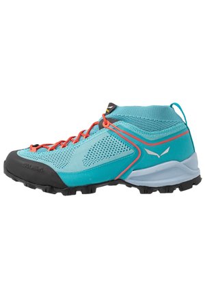 Chaussure de randonnée bleu clair avec lacets orange, embout noir, semelle intercalaire blanche et semelle adhérente, dotée d'un mesh respirant et d'un col montant au niveau de la cheville.