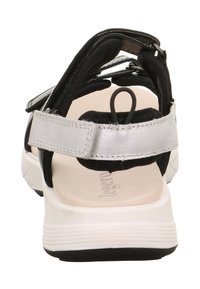 Czarna i srebrna sandał z solidnym paskiem na pięcie, regulowanym zapięciem na rzep oraz wyściełaną wkładką z jasnymi detalami.