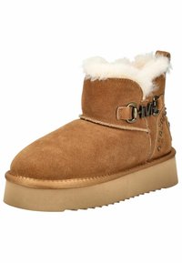 Bruine suède enkellaars met schapenvachtvoering, een band met een metalen gesp en decoratieve studs aan de zijkant. Dikke rubberen zool.