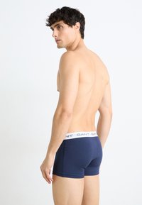 Boxeri scurți din bumbac bleumarin cu un brâu elastic alb pe care este inscripționat logo-ul GANT, concepuți pentru confort și o potrivire strânsă.