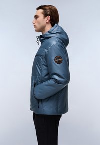 Blue puffer jacket with adjustable hood, side pockets, and an orange circular logo on the left sleeve. Smooth, reflective fabric.
