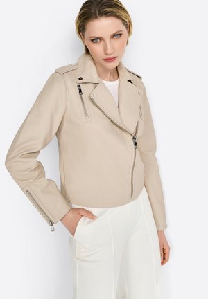 Beige Leder-Bikerjacke mit asymmetrischem Reißverschluss, Reißverschlusstaschen und Schulterklappen-Details. Enganliegende Passform mit glatter Textur.