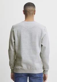 Gray sweatshirt with a round neckline, long sleeves, and ribbed cuffs and hem. Soft texture with a smooth finish. Casual design.
