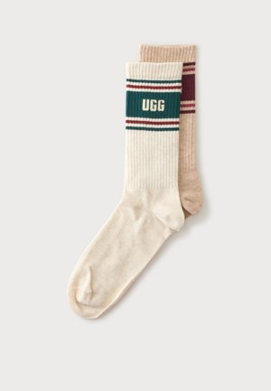 Paire de chaussettes côtelées, une beige avec des rayures bordeaux, une écrue avec des rayures vertes et bordeaux et texte "UGG" sur le bord-côte.