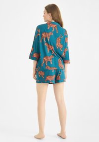 Conjunto de pijama de manga corta en turquesa con estampado de tigre naranja, de corte suelto y fabricado con un tejido ligero, diseñado para la comodidad.