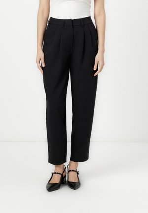 Black pleated trousers with a relaxed fit, featuring a smooth fabric and a mid-rise waist. Paired with black slingback heels.