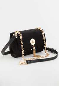 Sort suede håndtaske med en foldet rektangulær form, guld kædeda og læderrem, der har en dekorativ guldknap og frynser.