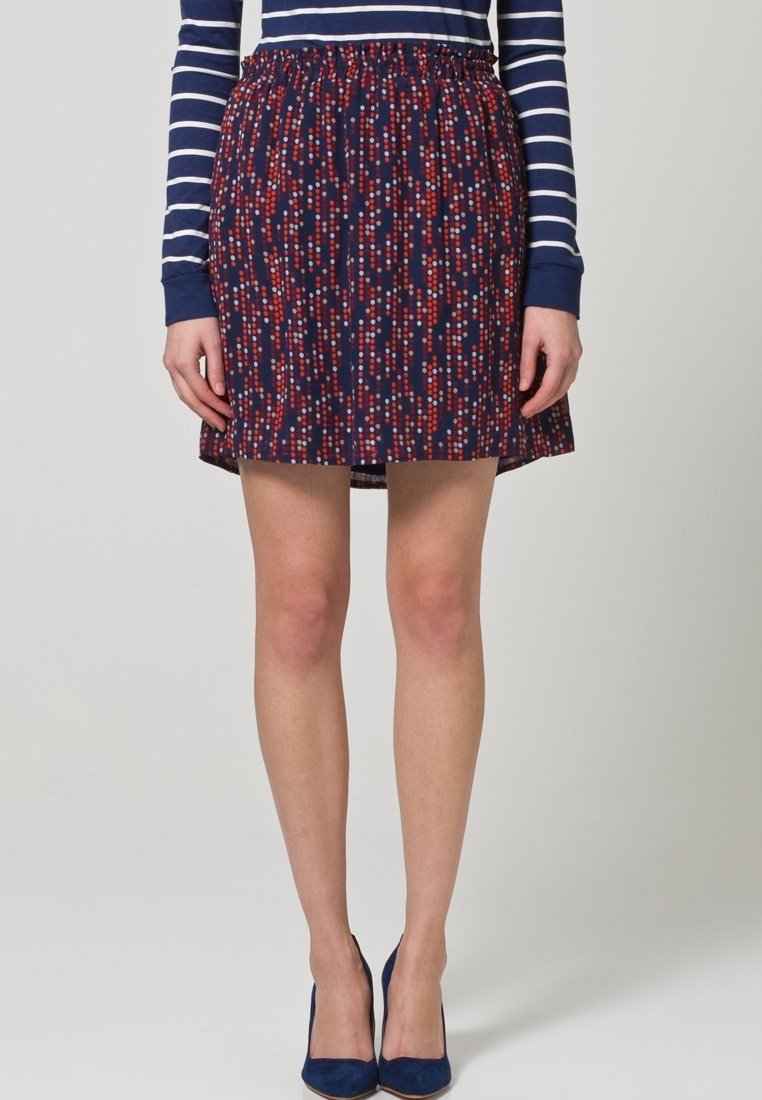 Jupe marine avec un motif à pois multicolores en rouge et bleu clair, dotée d'une taille élastique et d'un design évasé, atteignant le mi-cuisse.