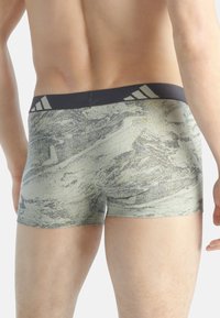 Pánské boxerky s abstraktním vzorem v světle zelené a šedé barvě, s černým elastickým pasem se bílými pruhy.