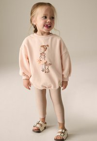 Rosa oversized sweatshirt med en tjej och kanin grafik. Randiga beige leggings och vita sandaler med spännen. Mjuk, avslappnad tyg.