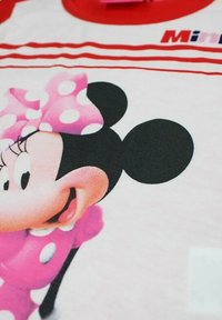 T-shirt pour enfants avec un col rouge, présentant une grande image imprimée d'un personnage de dessin animé avec des oreilles noires et un nœud rose à pois.
