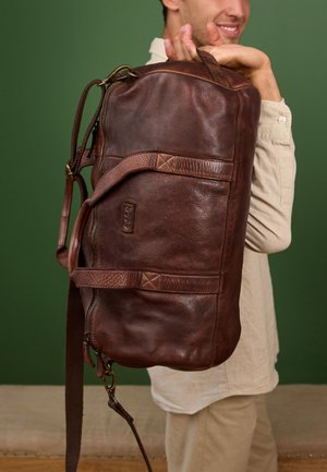 Brown leather duffel bag with multiple pockets, sturdy zippers, and a detachable shoulder strap. Textured finish with contrasting accents.