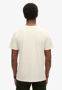 T-shirt cream a maniche corte in un fit rilassato, realizzato in tessuto morbido con una sottile texture, caratterizzato da un collo a giro e orlo dritto.
