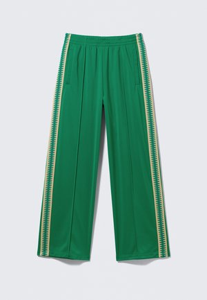 Green track pants with beige zigzag stripe along each side, elastic waistband, and side pockets, laid flat against a light background.